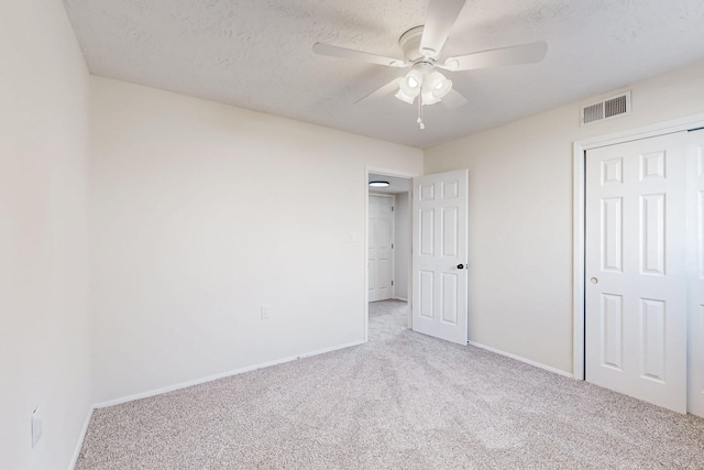 unfurnished bedroom featuring visible vents, ceiling fan, baseboards, carpet, and a textured ceiling