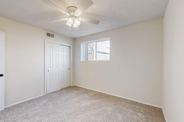 unfurnished bedroom featuring carpet, baseboards, visible vents, a closet, and a textured ceiling