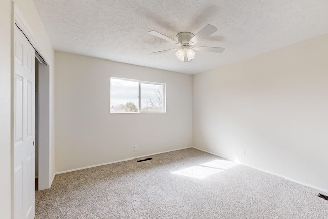 unfurnished bedroom featuring visible vents, a textured ceiling, a closet, carpet floors, and ceiling fan