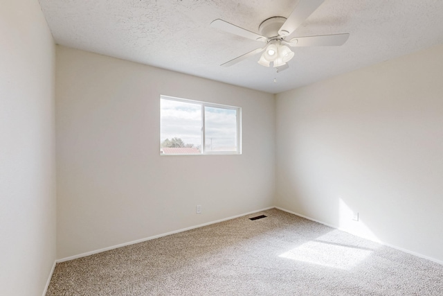 carpeted empty room featuring baseboards, a ceiling fan, visible vents, and a textured ceiling