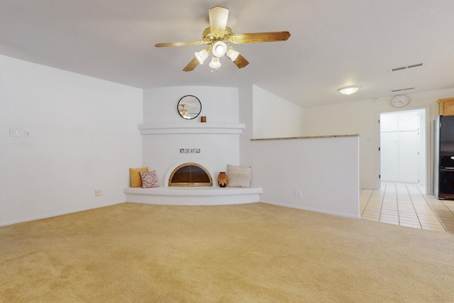 unfurnished living room with visible vents, light carpet, a glass covered fireplace, and a ceiling fan