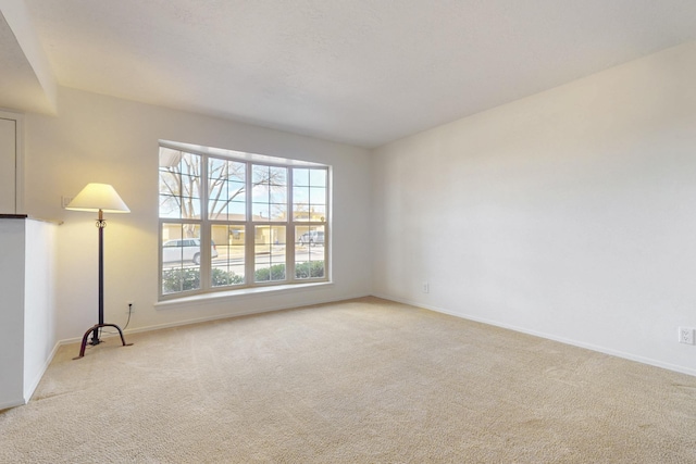 spare room featuring baseboards and light carpet