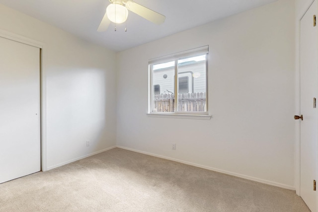 unfurnished bedroom with a closet, light carpet, baseboards, and a ceiling fan