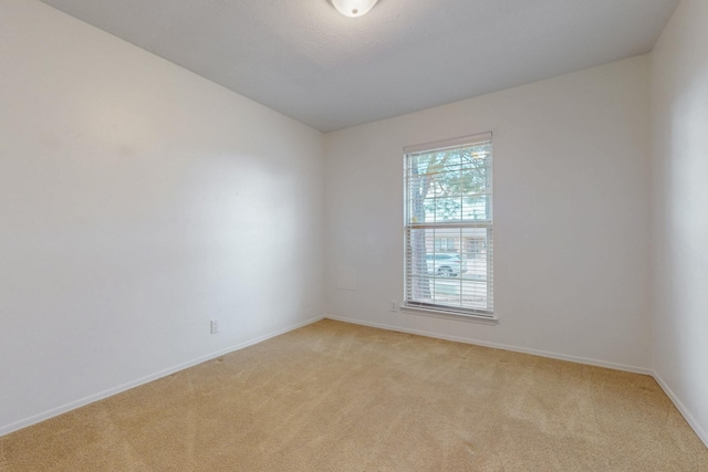 empty room featuring light colored carpet and baseboards