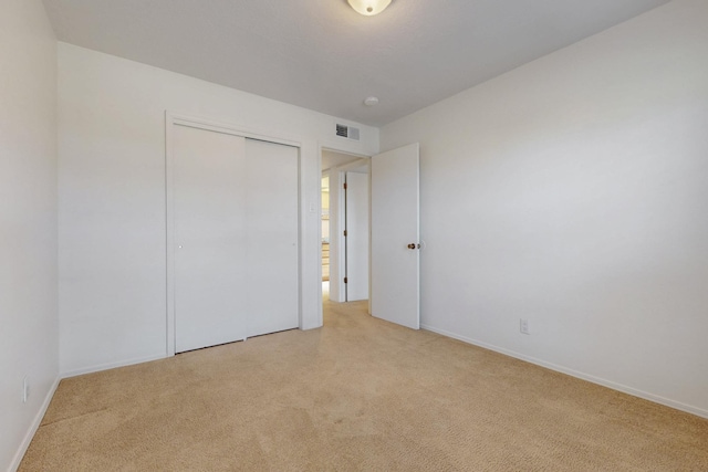 unfurnished bedroom with visible vents, a closet, and light carpet