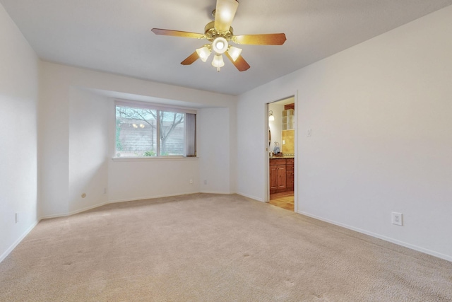 spare room with ceiling fan, baseboards, and light carpet