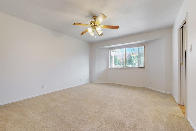 unfurnished room featuring baseboards, light colored carpet, and ceiling fan