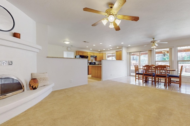 living area featuring a glass covered fireplace, recessed lighting, light tile patterned flooring, light colored carpet, and ceiling fan