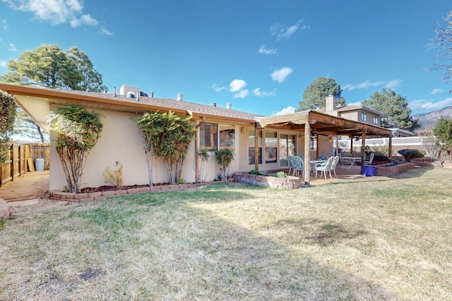 back of property featuring a patio area, stucco siding, a yard, and fence