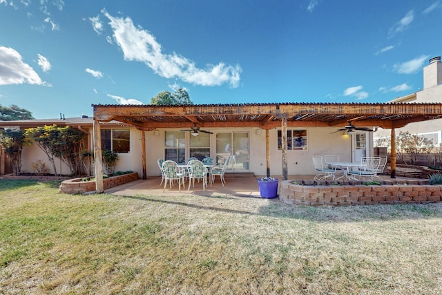 rear view of property featuring stucco siding, a lawn, and ceiling fan