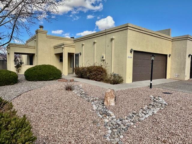 3239 Esplanade Cir SE, Rio Rancho, NM 87124 - view of front of property featuring a garage, concrete driveway, a chimney, and stucco siding