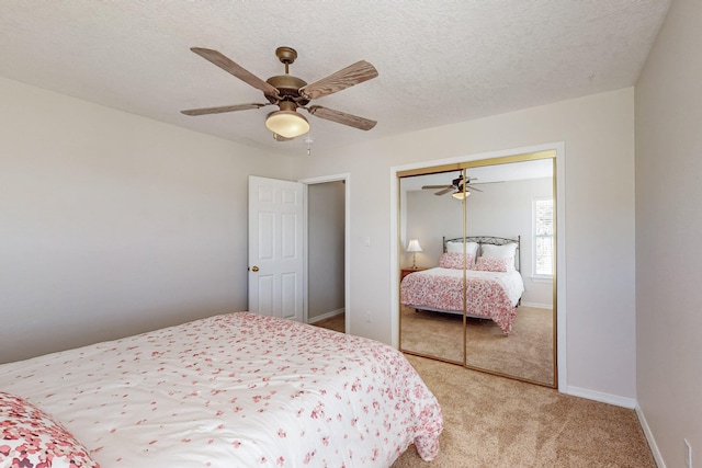 bedroom with baseboards, light colored carpet, a closet, a textured ceiling, and a ceiling fan