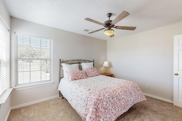 bedroom featuring baseboards, visible vents, ceiling fan, a textured ceiling, and light carpet