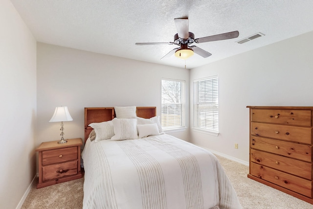 bedroom with baseboards, light colored carpet, visible vents, and a textured ceiling