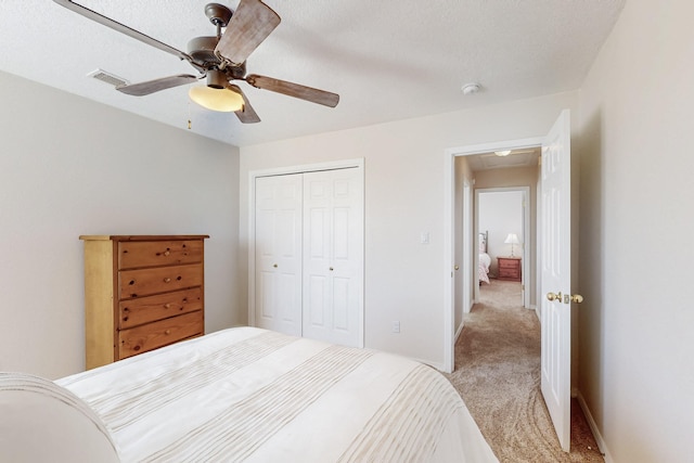 bedroom with baseboards, visible vents, a closet, and light carpet