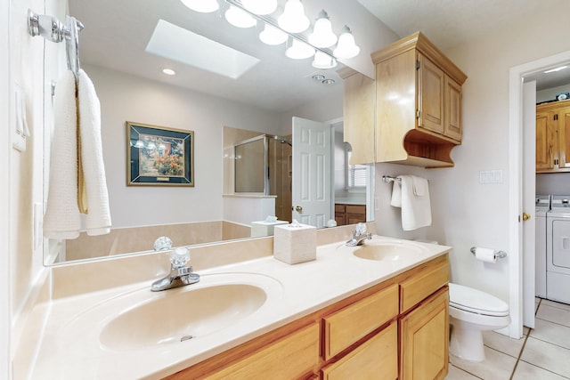 bathroom with a skylight, a stall shower, a sink, tile patterned floors, and washing machine and dryer