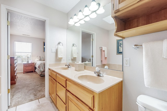 bathroom with double vanity, a textured ceiling, toilet, and a sink