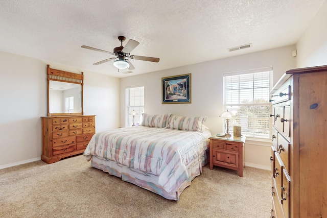 bedroom featuring a textured ceiling, baseboards, visible vents, and light carpet