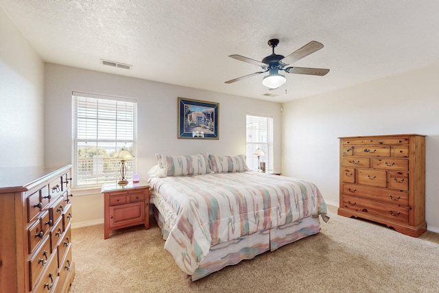 bedroom with visible vents, light carpet, and a textured ceiling