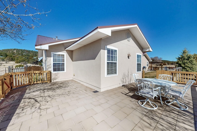 back of property featuring stucco siding, a patio, fence, metal roof, and outdoor dining area