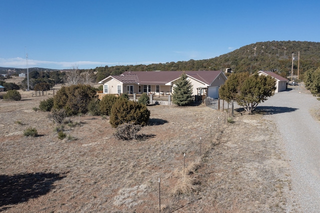 exterior space with a mountain view, metal roof, gravel driveway, and fence