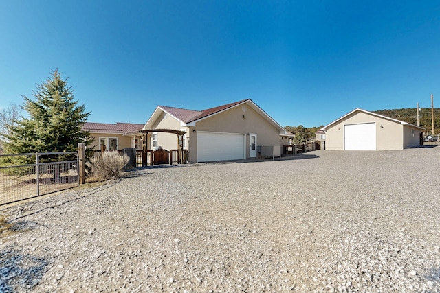 ranch-style house with stucco siding, an outbuilding, and fence