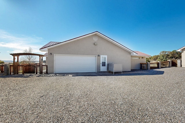 exterior space featuring a garage, metal roof, fence, and stucco siding