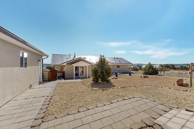 rear view of house featuring a patio, fence, and stucco siding