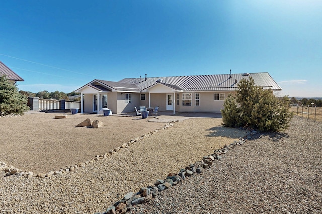 back of house featuring stucco siding, a patio, metal roof, and fence