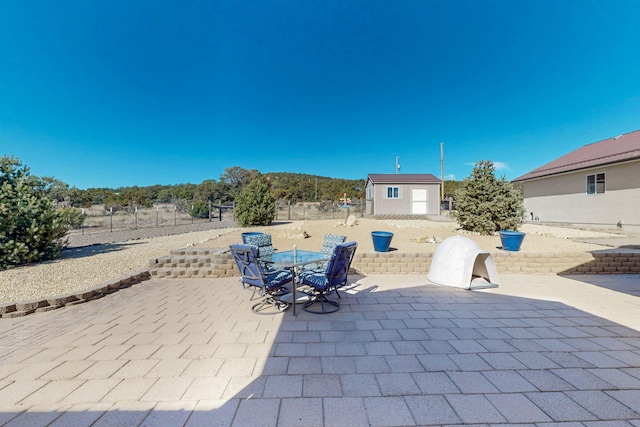 view of patio with outdoor dining area, an outdoor structure, and a shed