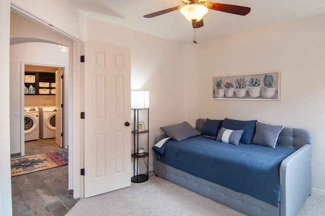 carpeted bedroom with washer and clothes dryer, arched walkways, and ceiling fan