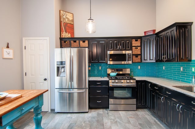 kitchen featuring a high ceiling, backsplash, appliances with stainless steel finishes, and hanging light fixtures