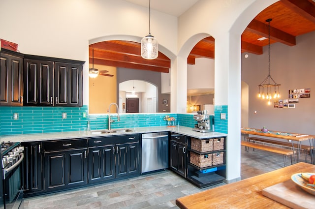 kitchen featuring a sink, decorative backsplash, stainless steel appliances, beamed ceiling, and ceiling fan with notable chandelier