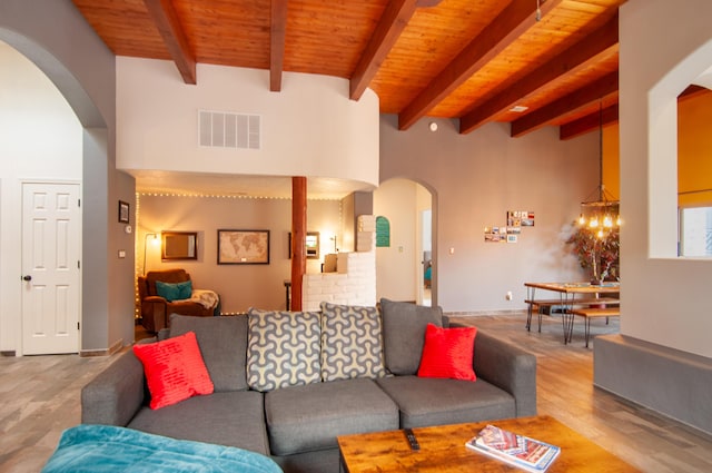 living area featuring visible vents, beamed ceiling, wood finished floors, arched walkways, and wooden ceiling