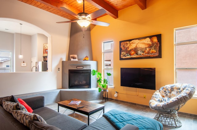 living room with beam ceiling, a fireplace, arched walkways, ceiling fan, and wooden ceiling