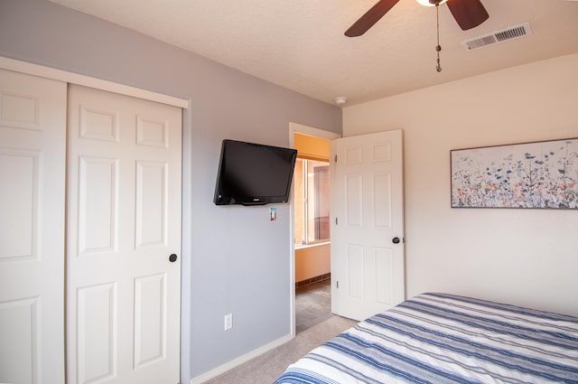 bedroom with visible vents, light carpet, a textured ceiling, baseboards, and ceiling fan