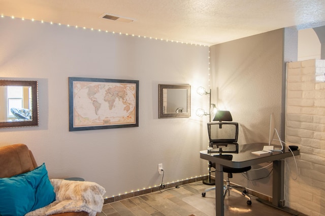 office area with visible vents, baseboards, a textured ceiling, and wood finished floors