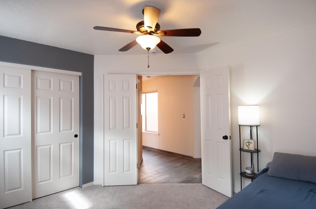 unfurnished bedroom with baseboards, arched walkways, ceiling fan, a closet, and light carpet