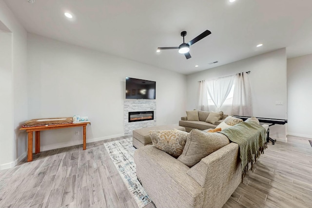 living room featuring baseboards, recessed lighting, wood finished floors, a glass covered fireplace, and a ceiling fan