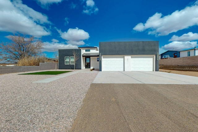 contemporary home with stucco siding, driveway, an attached garage, and fence