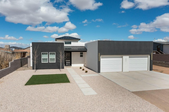 southwest-style home featuring stucco siding, a garage, fence, concrete driveway, and metal roof