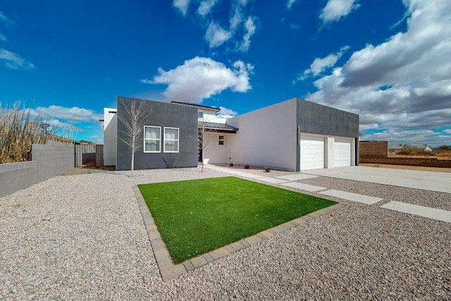 contemporary house featuring stucco siding, a garage, driveway, and fence