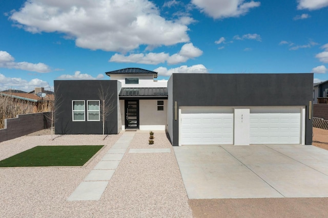 view of front of home with driveway, a standing seam roof, stucco siding, a garage, and metal roof