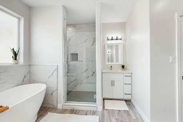 bathroom with a marble finish shower, a soaking tub, vanity, and wood finish floors