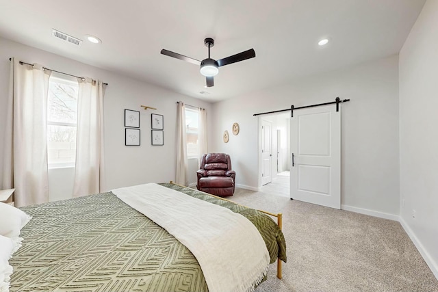 bedroom with a barn door, multiple windows, baseboards, and visible vents