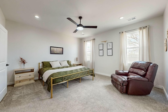 carpeted bedroom featuring visible vents, multiple windows, baseboards, and a ceiling fan