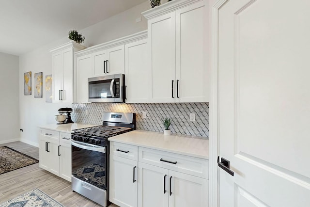 kitchen featuring light countertops, backsplash, light wood-style floors, and appliances with stainless steel finishes