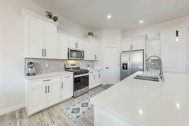 kitchen with decorative backsplash, white cabinets, appliances with stainless steel finishes, and a sink