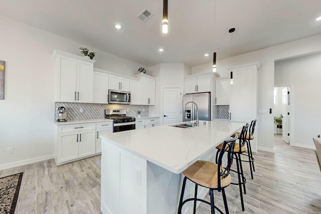 kitchen featuring decorative backsplash, a kitchen breakfast bar, visible vents, and stainless steel appliances