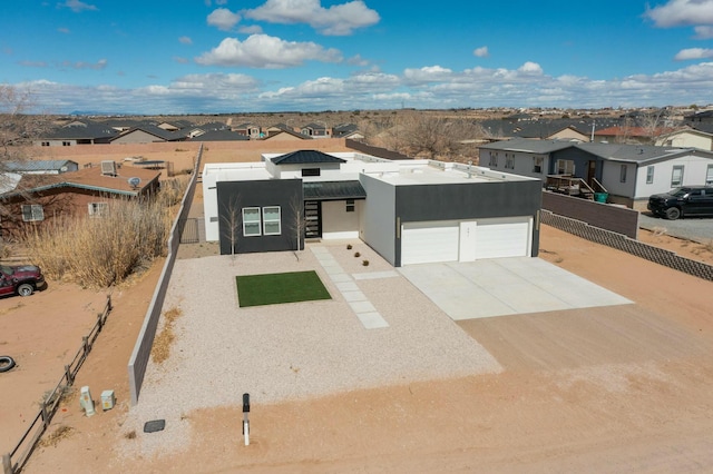 adobe home featuring stucco siding, driveway, fence, a residential view, and an attached garage